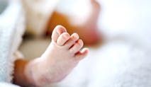 Newborn baby on a white and light blue blanket - tiny baby feet closeup.