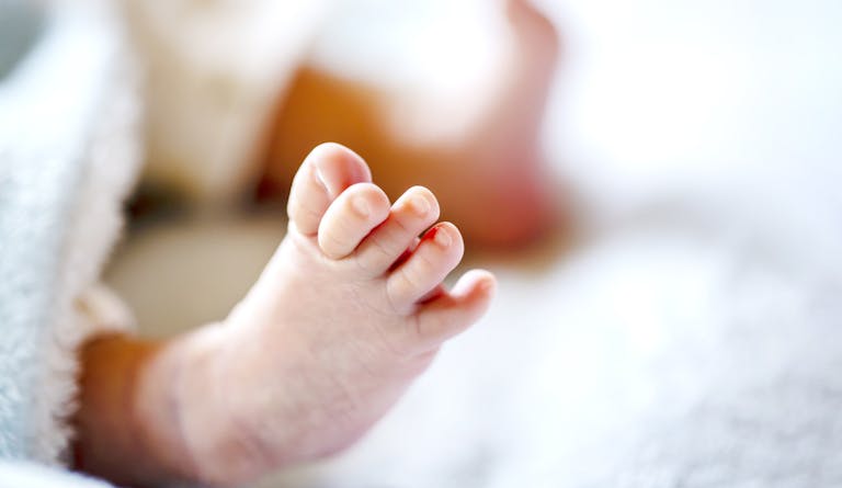 Newborn baby on a white and light blue blanket - tiny baby feet closeup.