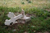 Fallen cross lying on grass symbolizing loss and grief.