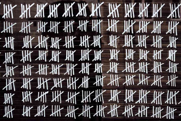 Photo: Dóra Bíró (Getty Images/iStockphoto) Counting stripes calendar. Handmade tally marks written on the wall by white chalk. Endless pandemie lockdown, longtime prison, waiting for the summer, ancient counting methods concept.