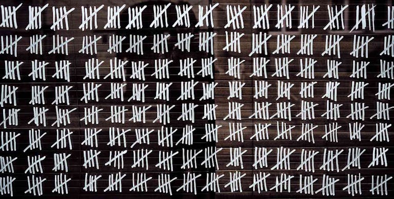Counting stripes calendar. Handmade tally marks written on the wall by white chalk. Endless  pandemie lockdown, longtime prison, waiting for the summer, ancient counting methods concept.
