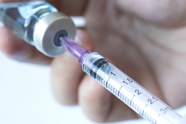 Photo: Ake Ngiamsanguan/Getty Images Doctor's hand holds a syringe and a blue vaccine bottle at the hospital. Health and medical concepts stock photo