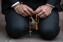 MADRID, SPAIN - 2023/05/19: A man kneeling on the ground prays holding a rosary during an anti-abortion protest in front of the Dator clinic. The Dator clinic is one of the accredited clinics in Spain for the voluntary termination of pregnancy.