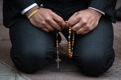 MADRID, SPAIN - 2023/05/19: A man kneeling on the ground prays holding a rosary during an anti-abortion protest in front of the Dator clinic. The Dator clinic is one of the accredited clinics in Spain for the voluntary termination of pregnancy.