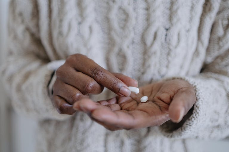 Close-up of unrecognizable black woman holding pills