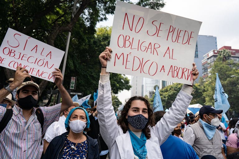 Photo by Lexie Harrison-Cripps/SOPA Images/LightRocket via Getty Images MEXICO CITY, MEXICO - 2021/10/03: A demonstrator holds a placard reading "You cannot force a doctor to abort" during the pro-life demonstration march. Thousands march in Mexico City at a pro-life and pro-women demonstration march. Demonstrators came in from all over the country, with different states or organizations written on their t-shirts. The march comes after the Mexican Supreme Court ruled that abortion is no longer a crime since September 2021.