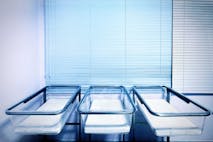 Photo: vasiliki/Getty Images Baby cribs at a maternity ward. Low birth rate and fertility concept.