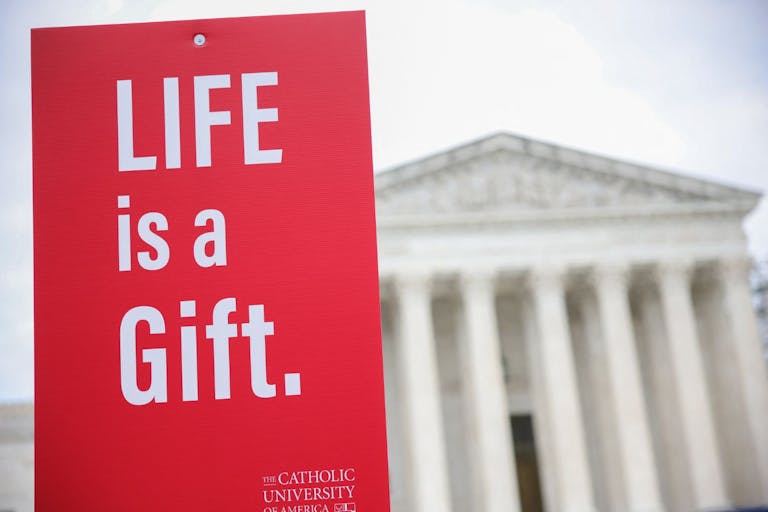Photo by BRYAN DOZIER/Middle East Images/AFP via Getty Images A protest sign is held in the air outside of the Supreme Court during the 52nd annual March For Life in Washington, D.C. on January 24, 2025.