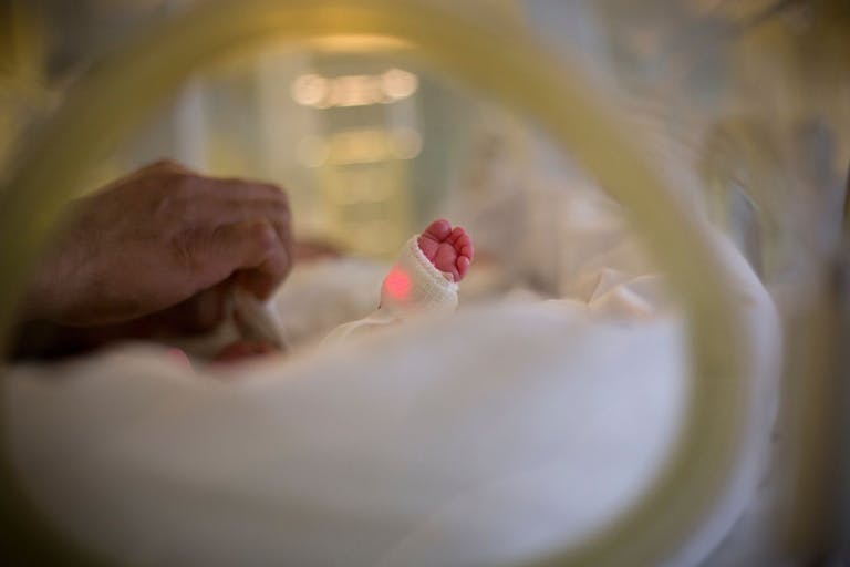 Photo: Mayte Torres/Getty Images Newborn baby's feet and dad's hand - stock photo