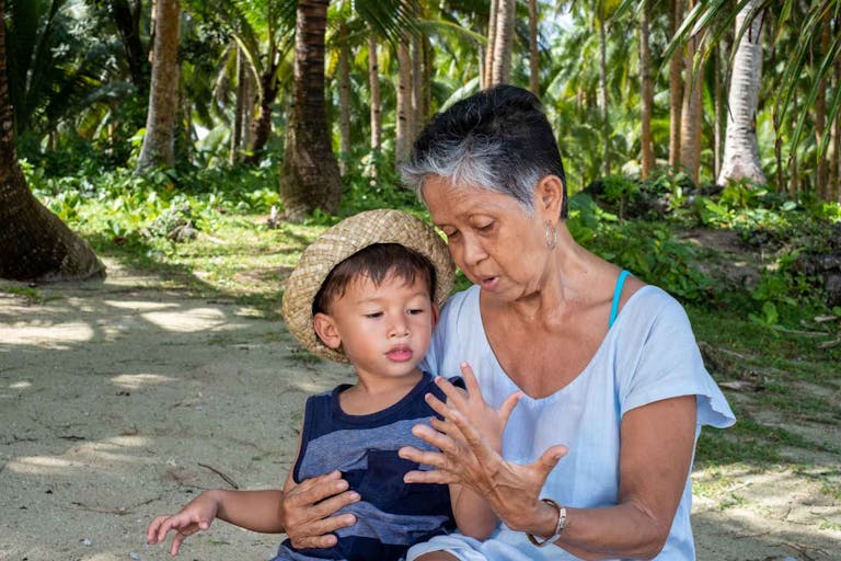 Photo: DutcherAerials via Getty Images/iStock Photo Grandmother bonds with grandson on the beach in the Philippines