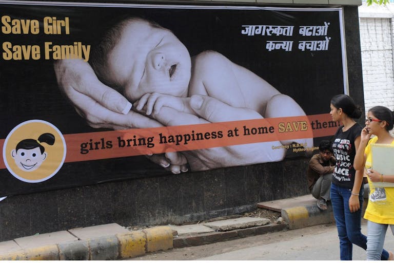 Photo: RAVEENDRAN/AFP via Getty Images Young Indian women walk past a billboard in New Delhi on July 9, 2010, encouraging the birth of girls. Mostly as a result of sex-selective abortion, India is one of the few countries worldwide with an adverse child sex ratio in favour of boys. Under Indian law, tests to find out the gender of an unborn baby are illegal if not done for medical reasons, but the practice continues in what activists say is a flourishing multi-million-dollar business. Girls in India are often considered a liability, as parents have to put away large sums of money for dowries at the time of their marriage.