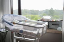 Photo: WePro/Getty Images Empty crib by the window, stroller - stock photo