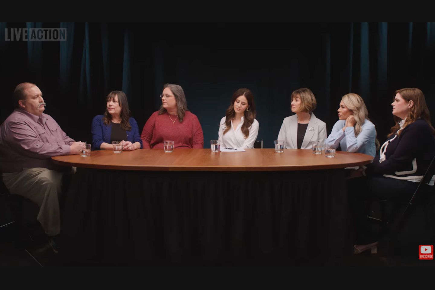 Panel of men and women sit around a table discussing abortion after rape.