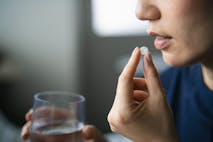 Photo: d3sign/Getty Images Close-up shot of Asian woman holding a glass of water taking pills at home. Healthcare, illness, supplements and medication safety concept