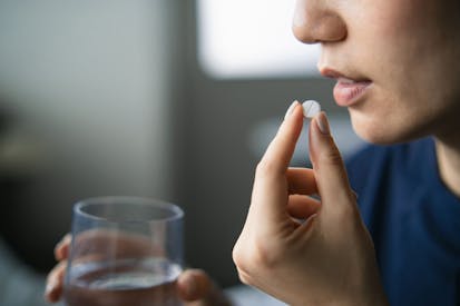 Photo: d3sign/Getty Images Close-up shot of Asian woman holding a glass of water taking pills at home. Healthcare, illness, supplements and medication safety concept