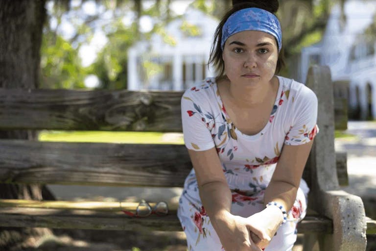 Photo: Alliance Defending Freedom Rosalie Markezich sits on a bench wearing a blue headband and a white dress with organ and green leaves.