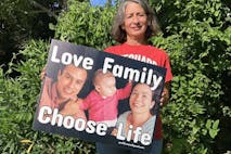Photo: Pro-Life in the Public Square woman holds yard sign that says "Love Family, Choose Life"