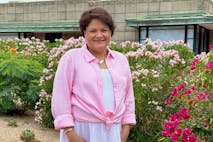 Photo provided to Live Action News Image shows a woman with short brown hair and a pink blouse, smiling in front of a garden.