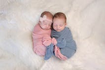 Stock Photo: Katrina Elena Photography/Getty Images Two month old, boy and girl fraternal twin babies. They are sleeping and swaddled together in pink and blue wraps that are tied together in a bow.