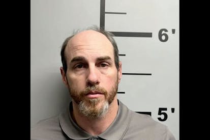 Image shows the mugshot of a balding white man with a beard.