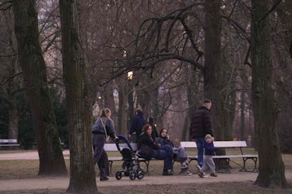 People watch as a woman with a baby stroller walks past in the Saxon Park, in Warsaw, Poland on 06 March, 2025.