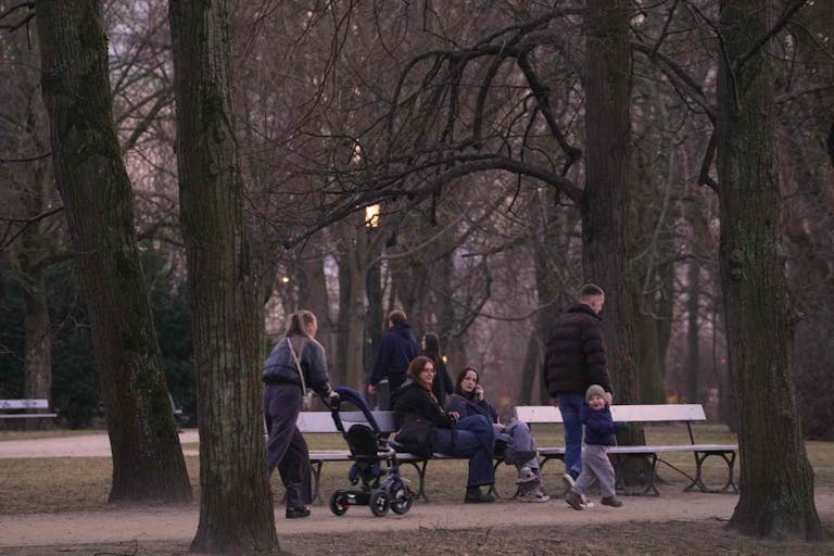 People watch as a woman with a baby stroller walks past in the Saxon Park, in Warsaw, Poland on 06 March, 2025.