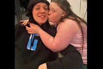 Photo: Aitch/Instagram A man smiles as his sister with Down syndrome kisses him on the cheek.