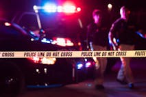 Photo: kali9/Getty Images Two multi-ethnic police officers standing in front of patrol cars, behind police tape, wearing bulletproof vests and duty belts. The policewoman is a mature African-American woman in her 40s. Her partner is a mid adult man in his 30s. It is nighttime and the emergency lights on top of the vehicles are flashing. The focus is on the cordon tape in the foreground.