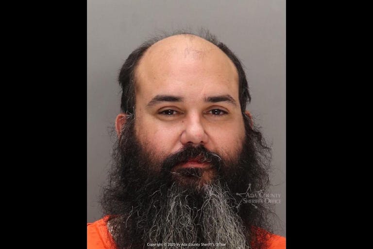 Image shows the mugshot of a balding man with a long beard.
