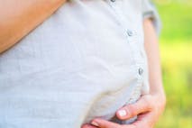 Photo: Melnikof/Getty Images birth giving, anniversary, womanhood concept. close up of belly of pregnant woman who is wearing minimalistic cotton shirt in blue colour, she is hugging her tummy