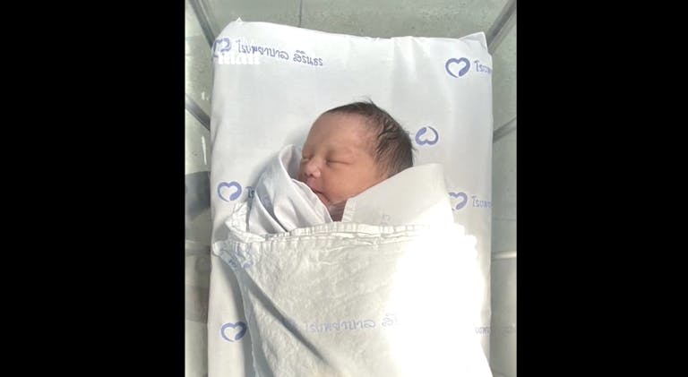 newborn baby girl abandoned in toilet tank in Bangkok, Thailand, lays in bassinet