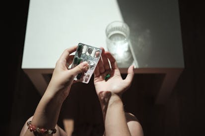 Photo: Mementojpeg/Getty Images Female hands holding pills and glass of water, taking medicine in morning - stock photo