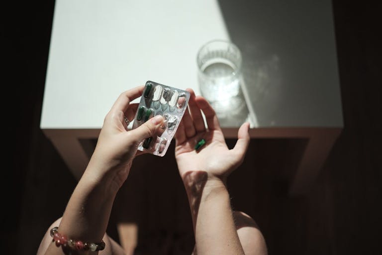 Photo: Mementojpeg/Getty Images Female hands holding pills and glass of water, taking medicine in morning - stock photo
