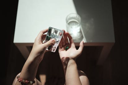 Female hands holding pills and glass of water, taking medicine in morning - stock photo