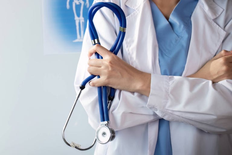 Confident healthcare professional holding stethoscope in medical office.