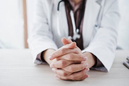 Female doctor with hands clasped in medical clinic.