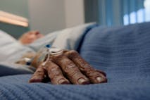 Photo: Bevan Goldswain/Getty Images Elderly man, hands and bed in hospital for with iv drip for stroke, healthcare and medicine. Senior patient, sleeping and gurney in clinic for cancer, health and life extension drugs with metmorfin