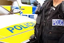 Photo: Lawrey Anstis/Getty Images Close-up of anonymous police officer wearing stab proof vest uniform and gear worn by constablury at the scene of an event. They are in front of emergency services police force vehicles featuring a cop car and police van, in response to an incident. Officers provide law enforcement, establish public order and protect citizens.