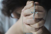 female hand holding rosary beads