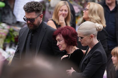 Photo: Christopher Furlong/Getty Images BIRMINGHAM, ENGLAND - JULY 30: Jack Osbourne, Sharon Osbourne, Kelly Osbourne and family members stop to view tributes to the late Ozzy Osbourne from fans at Black Sabbath Bench and Bridge as his funeral cortege travels through his home city of Birmingham on July 30, 2025 in Birmingham, England. The Black Sabbath frontman passed away on July 22nd at the age of 76. His death occurred just a little over two weeks after his final live performance at the 'Back to the Beginning' concert in his hometown of Birmingham.