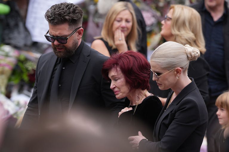 Photo: Christopher Furlong/Getty Images BIRMINGHAM, ENGLAND - JULY 30: Jack Osbourne, Sharon Osbourne, Kelly Osbourne and family members stop to view tributes to the late Ozzy Osbourne from fans at Black Sabbath Bench and Bridge as his funeral cortege travels through his home city of Birmingham on July 30, 2025 in Birmingham, England. The Black Sabbath frontman passed away on July 22nd at the age of 76. His death occurred just a little over two weeks after his final live performance at the 'Back to the Beginning' concert in his hometown of Birmingham.