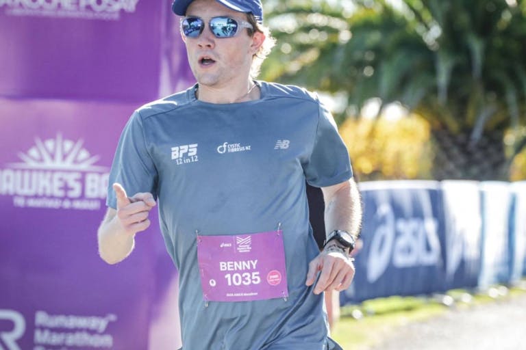 Ben Prince-Saxon is running, wearing a blue shirt, hat, and sunglesses.
