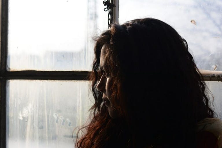 A woman looks out a window.