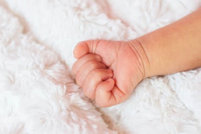 Infants hand on a white blanket.