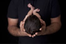 Photo: Shutterstock 173121728 Image shows man holding baby with dark hair.