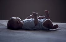 baby laying on white surface with face turned away from the camera