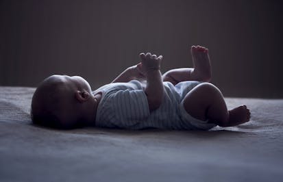 baby laying on white surface with face turned away from the camera
