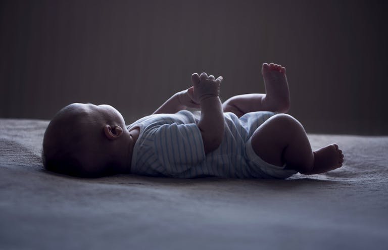 baby laying on white surface with face turned away from the camera
