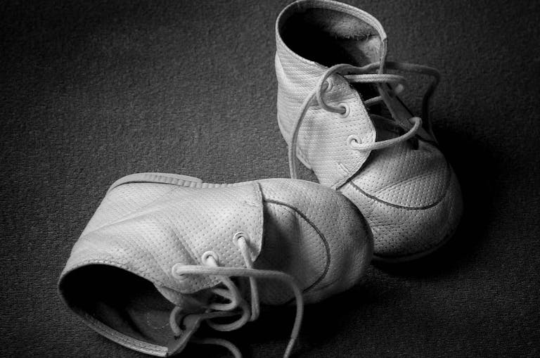 Pair of old tiny baby shoes. Black and white with copyspace.
