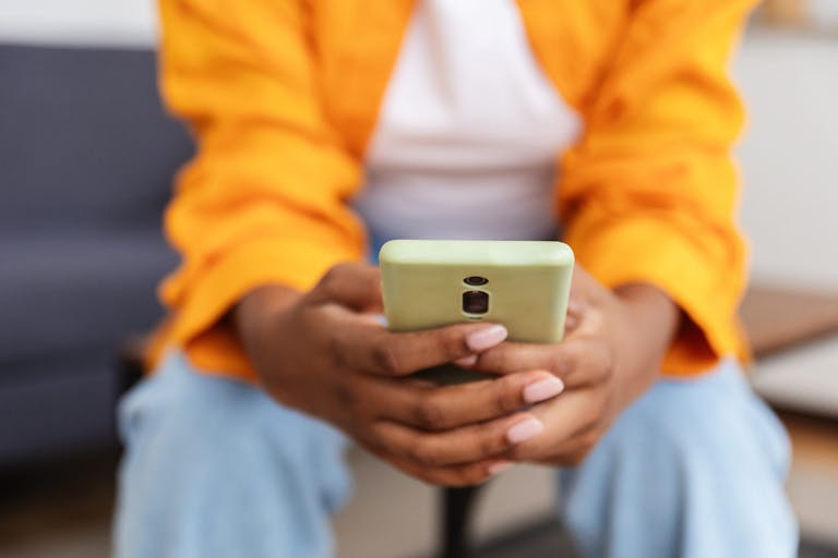 Close-up of a young black woman using her smart phone, browsing the internet, mobile apps or social media